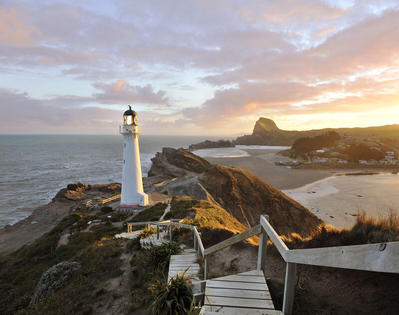 Coastal lighthouse overlooking Wellington’s rugged shoreline and surrounding bays at sunset.