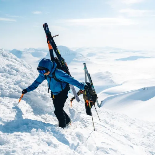 Ski trekkers climbing a snowy mountain with a view of mountains in the background